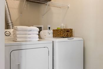 A white washing machine and dryer with towels on top of the dryer.